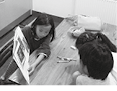 『川中島の保健室』で　小学生の姉が　妹に本を読み聞かせている様子の写真